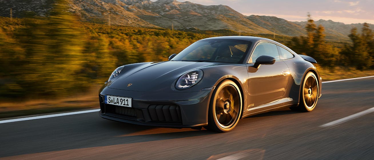 Porsche 911 Carrera GTS driving, rugged mountains behind