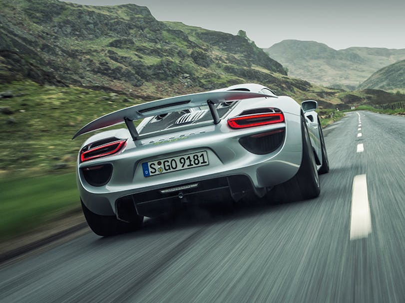 Silver Porsche 918 Spyder driving down a mountain road