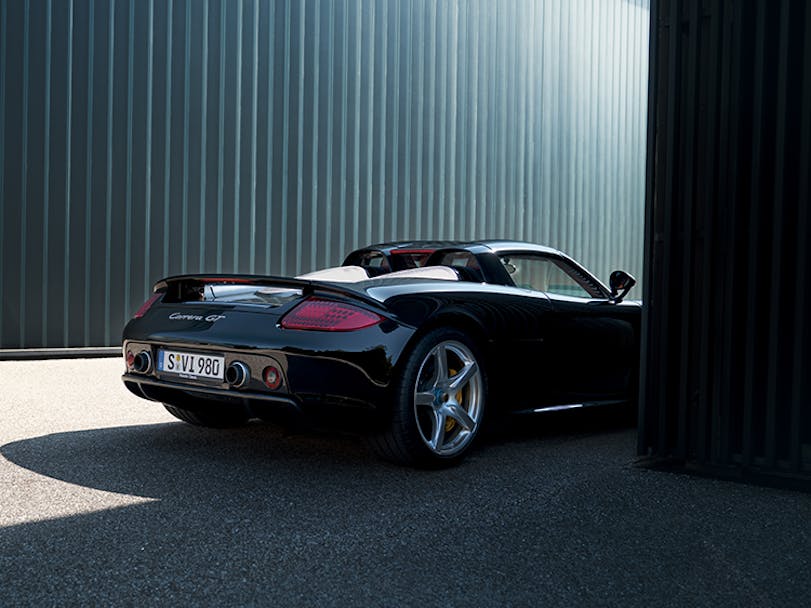 Rear half of Carrera GT peeking out from behind buildings