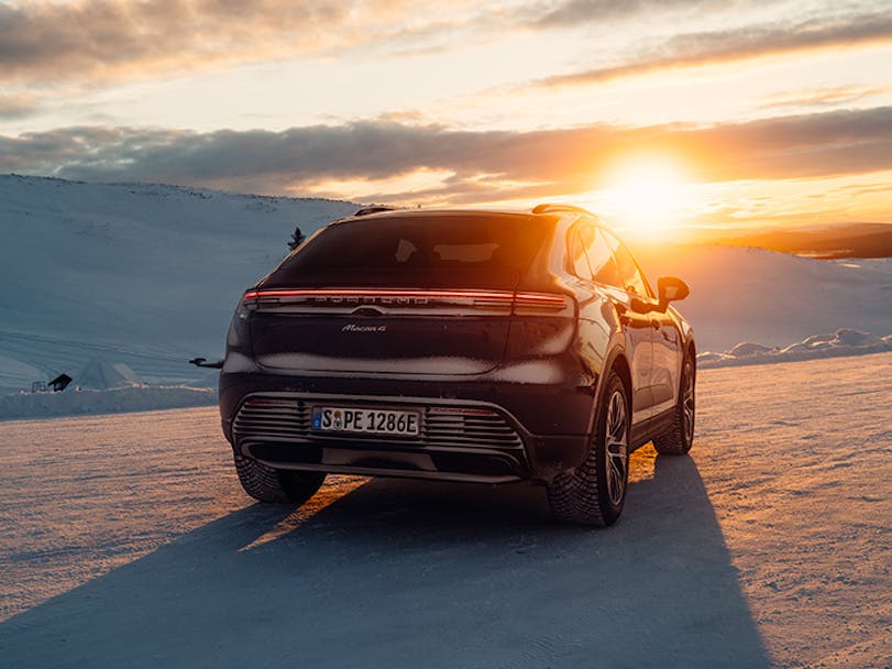 Porsche Macan 4 Electric in snowy scene, sun setting in distance